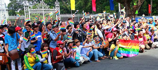 A group of people smiling and waving rainbow flags
