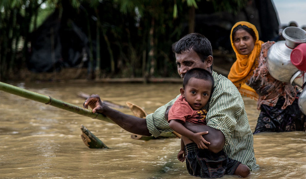 A father carries his son across a broken bamboo bridge on the edge of Balhukali camp, Bangladesh. Three days of heavy rains flooded many of the areas where people had set up temporary shelters, forcing them to move to higher ground. Photo Credit: Aurélie Marrier d