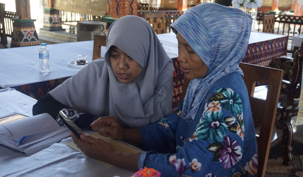 Two women learning how to use a tablet.