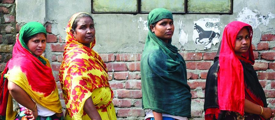 Four women wearing bright colours look into the camera with serious expressions