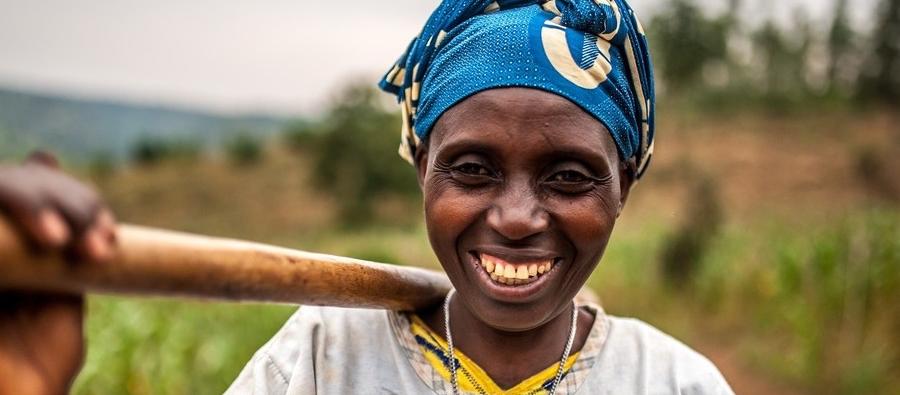 Woman smiling at the camera, holding a pole/stick on her shoulder