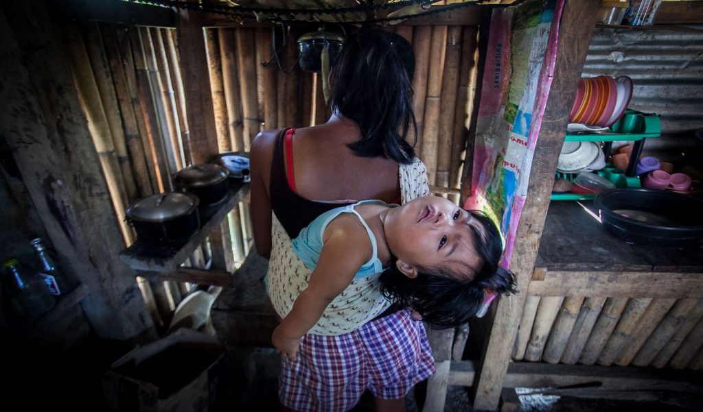 A woman carries a toddler in her back.