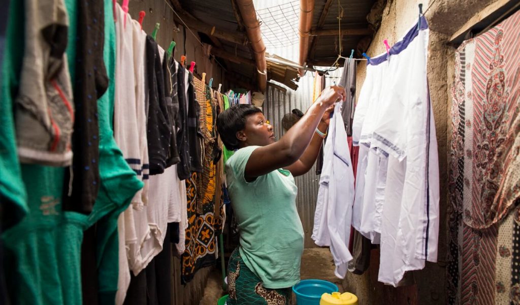 Black woman standing in an alley hanging her laundry to dry.