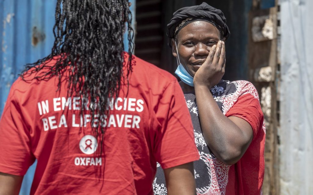 Oxfam worker with woman in red, hand on face.