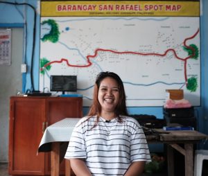 A young woman standing in front of a map while smiling