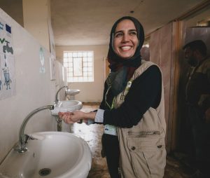 A woman washing her hands and smiling in a clean washroom somewhere in the Middle East region