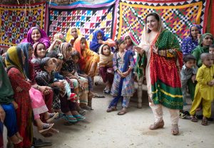 A woman wearing a colourful outfit, speaking to a group of women who are circled around her in Bangladesh