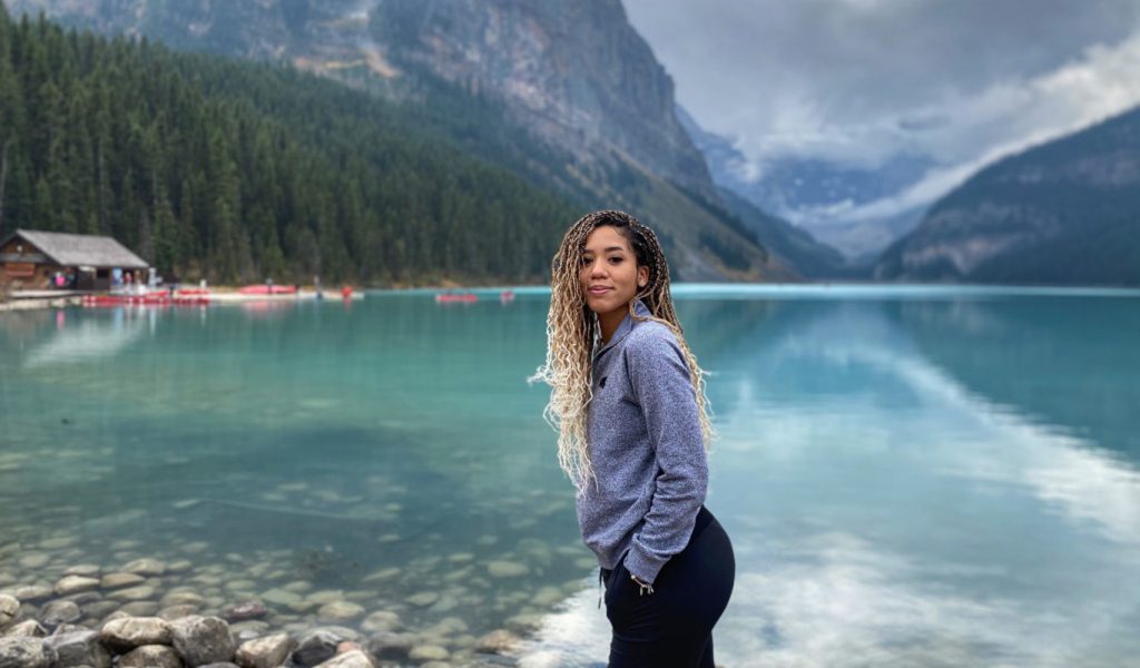 Woman standing in front of lake and mountains
