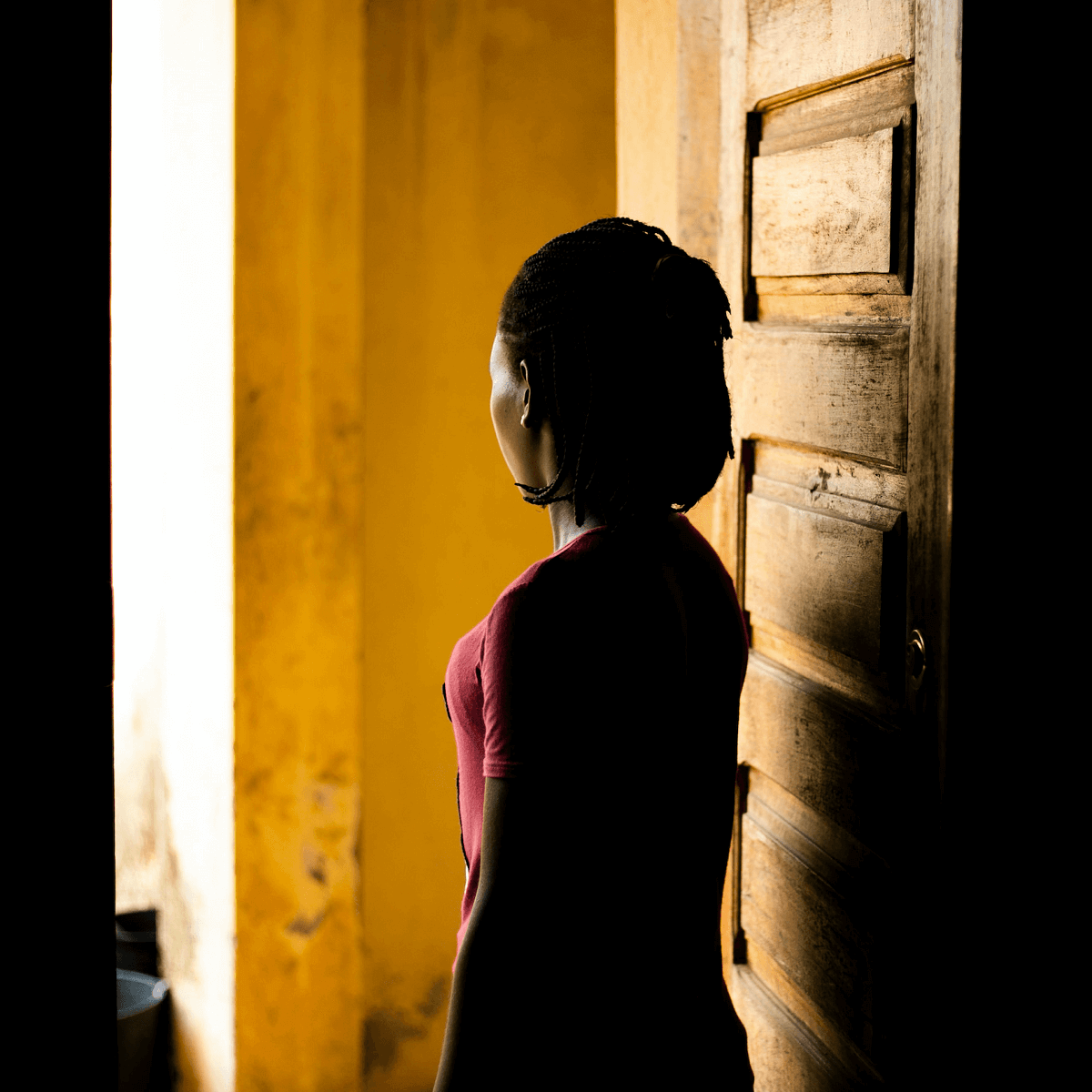 A person stands in a doorway with their back to the camera