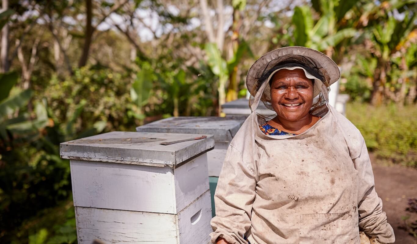 A smiling beekeeper near some bee hives