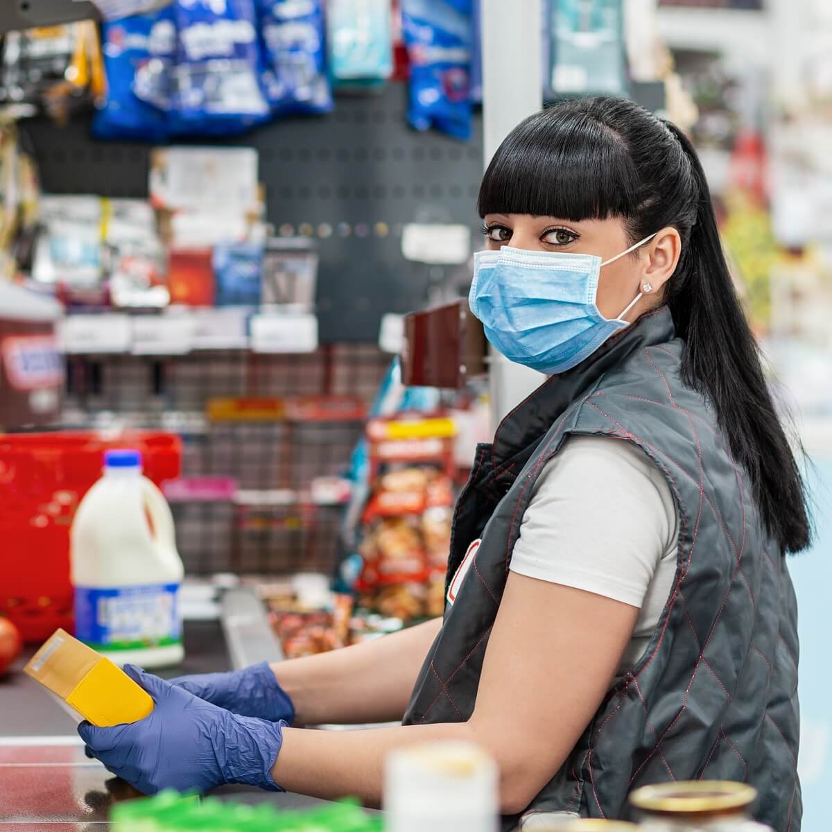 A cashier in a mask working at a store