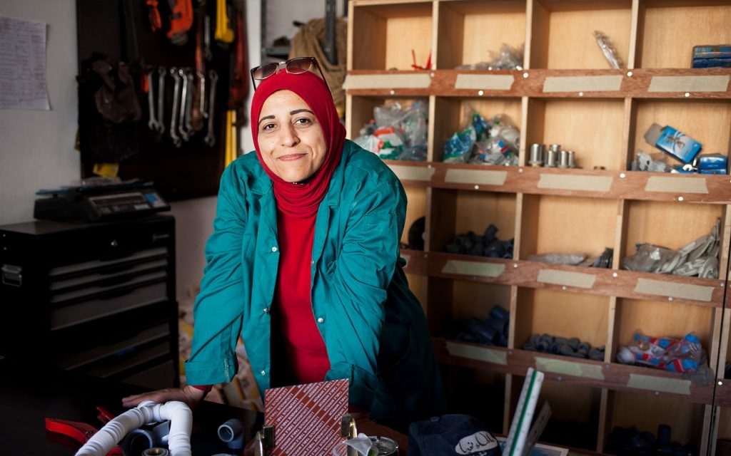 A woman in a red headscarf standing in a shop looking at the camera