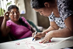 Two middle-aged women write on a piece of paper