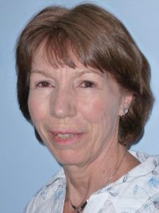 A Caucasian middle aged woman with short brown hair smiling.
