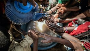 A group of people washing their hands from a blue pot