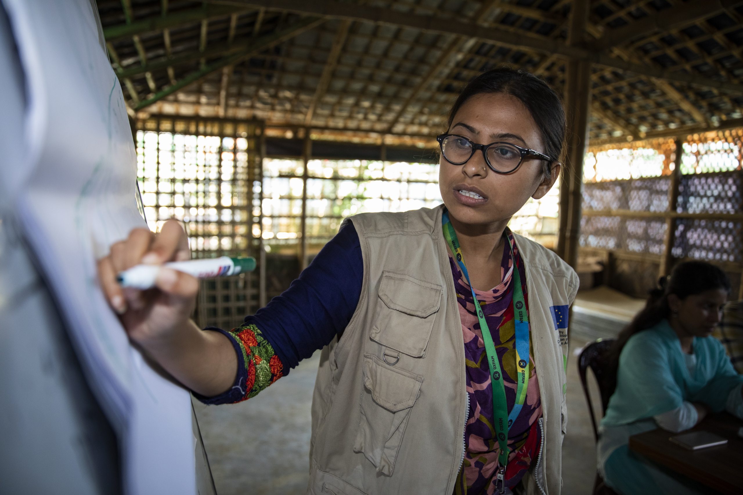 <p>Iffat Tahmid Fatema, Senior Innovation Officer in Public Health Promotion & Community Engagement, talks to the Oxfam team about community consultation tools for WASH infrastructure.</p>
<p> </p>
<p>The women’s social architecture project aims to put users at the centre of the design process, and brings in the expertise of architects to help create facilities and spaces that meet the needs of women and girls.</p>
<p>The project has developed jointly between Oxfam’s WASH, Protection and Gender teams, with architects and groups of women and adolescent girls living in the camps to explore the issues they face in using current WASH facilities (like toilets and bathing cubicles), to create new designs that overcome these issues and pilot the build of these designs in four locations. The project aims to showcase how stronger collaboration with refugees can create facilities that are more appropriate in terms of gender, culture, safety and dignity.<br />
<br />
Oxfam and the Rohingya women designed four different structures in different camps, one by one. This way, they could capture the learning and apply it to each new structure. For each one, the process was long: an initial consultation, a validation session to review the draft design, site selection consultations, final tweaks after construction, and finally an opening ceremony. On a visit to one site, refugee women point out to a visitor the changes that they made to the design –after a third round of consultations – including a pole next to the toilet that pregnant women can grab onto for balance as they squat, and a bench seat in the shower room, so they can sit as they have their bath.</p>