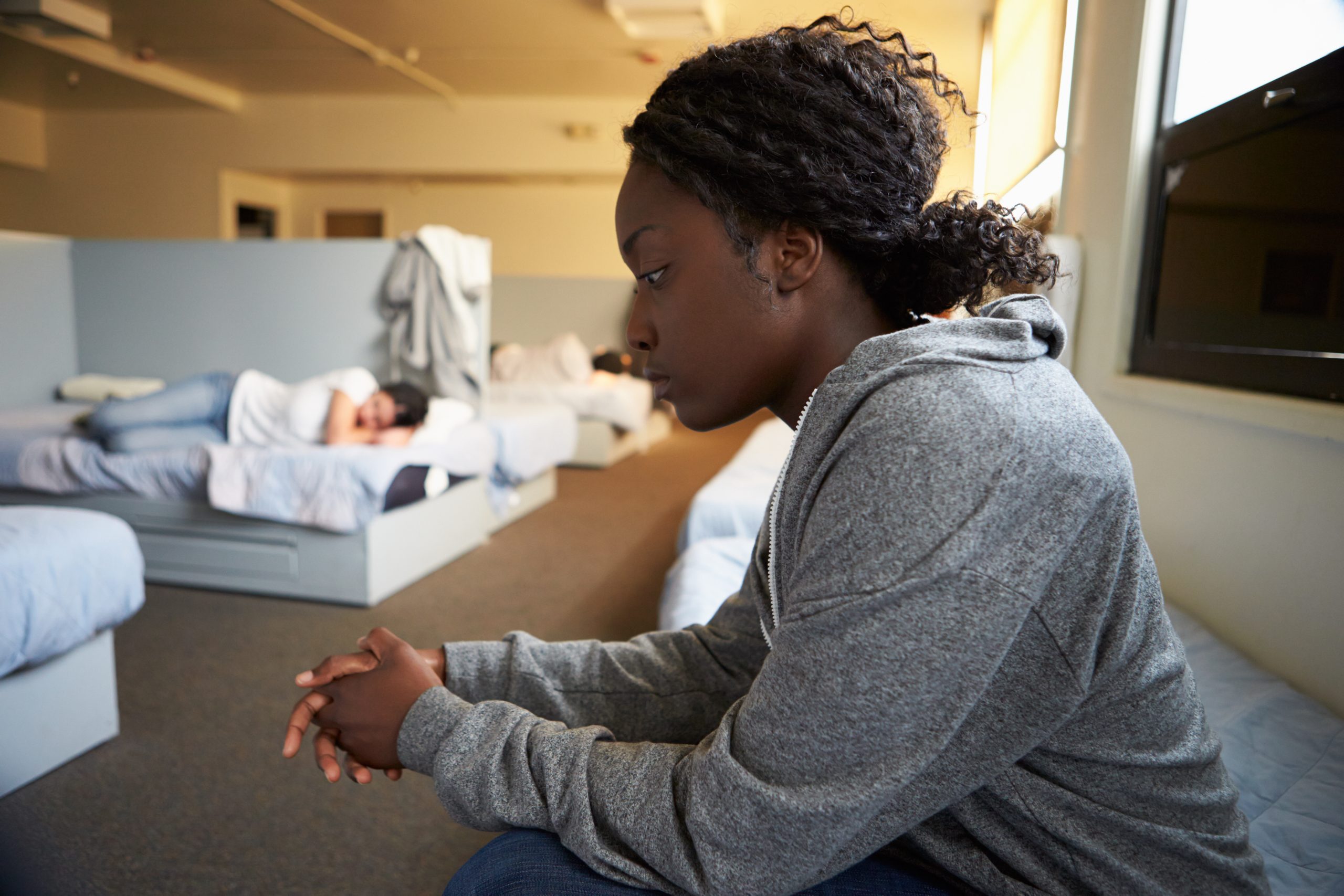 Women,Sitting,On,Beds,In,Homeless,Shelter