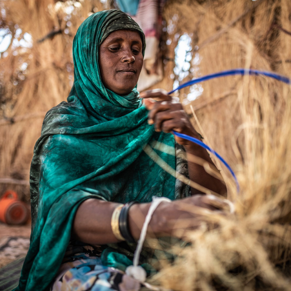 A woman is weaving a basket.