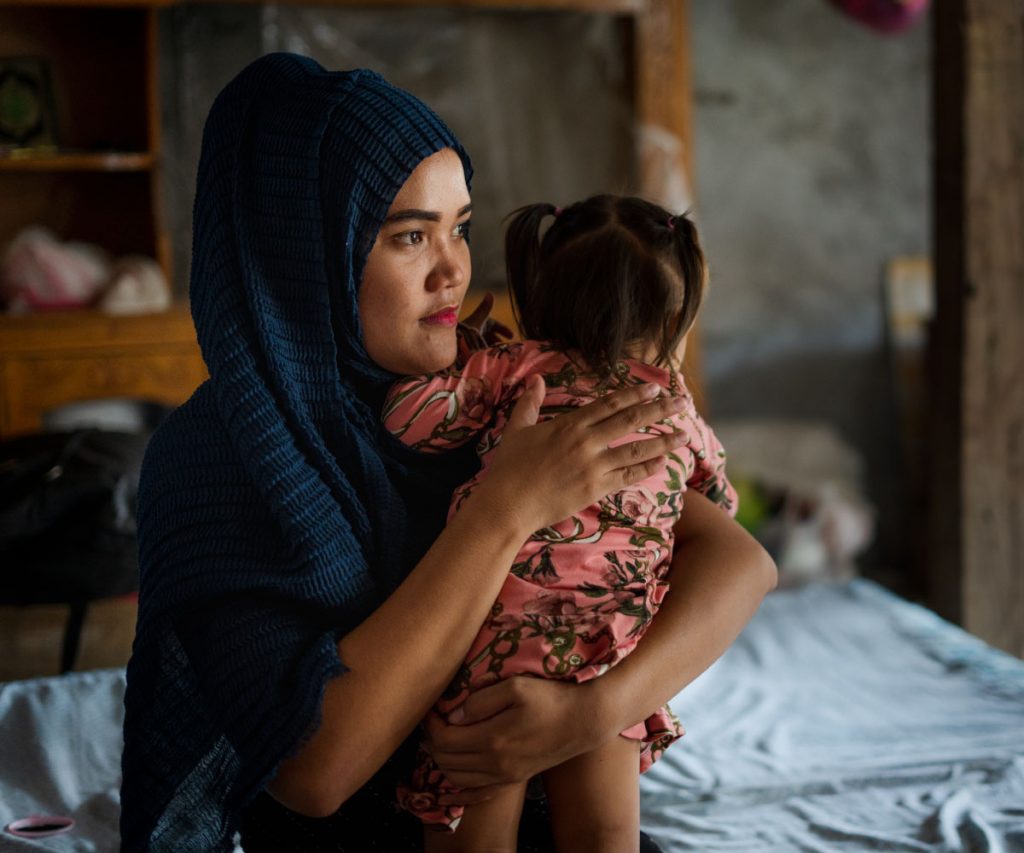 A young woman holds a baby.