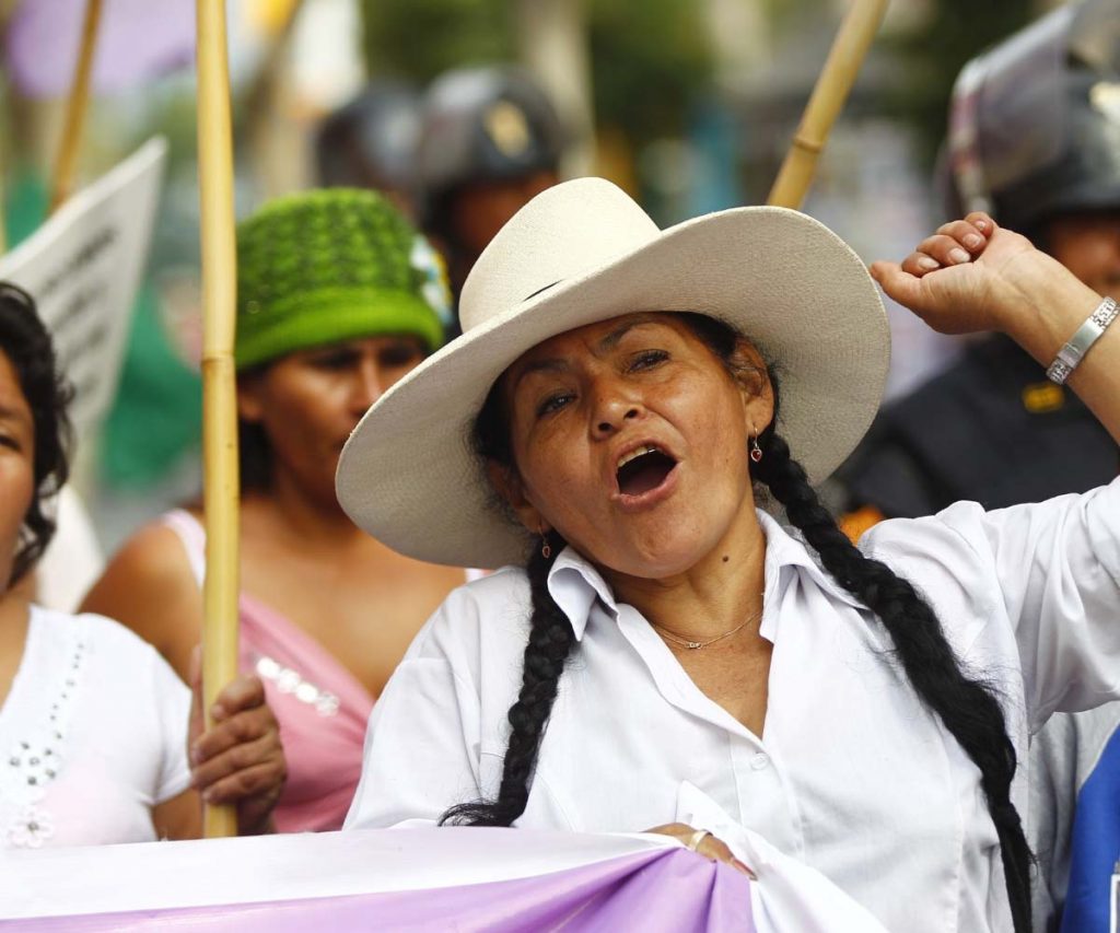 A woman wearing heat is seen talking while marching the streets in a protest.