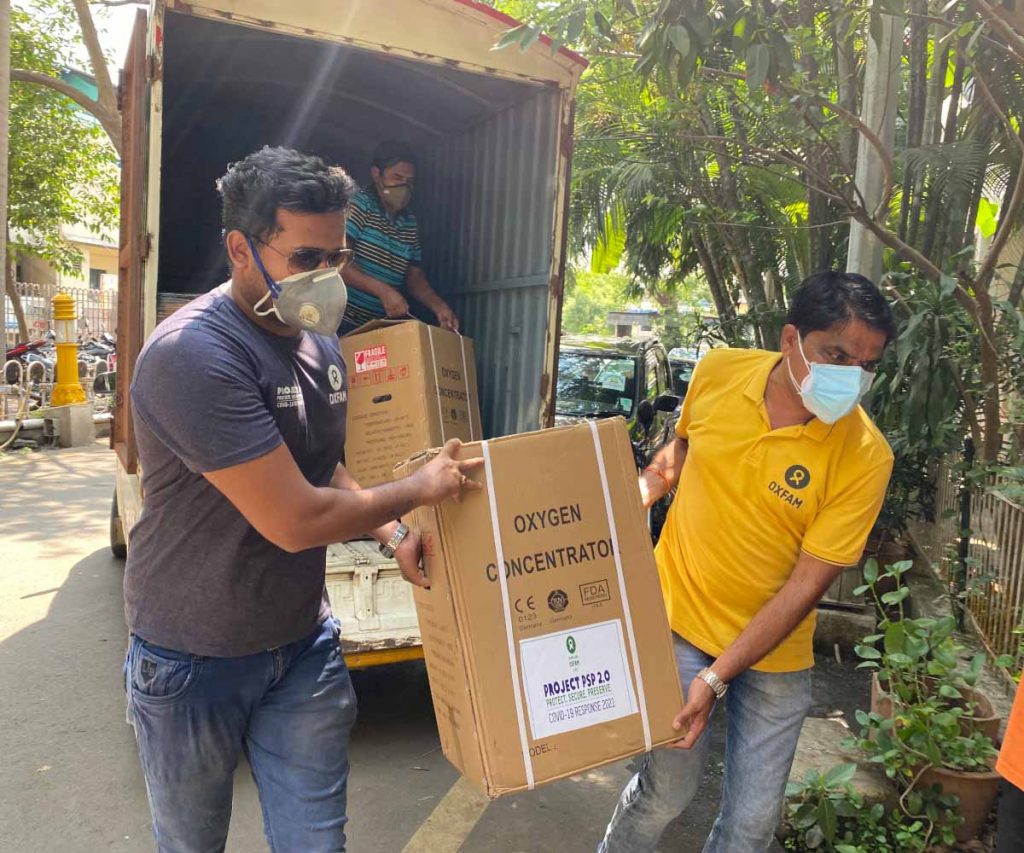 Men transport oxygen concentrators out of a truck.