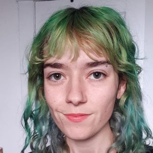 A young person with long green and blue hair, smiling.