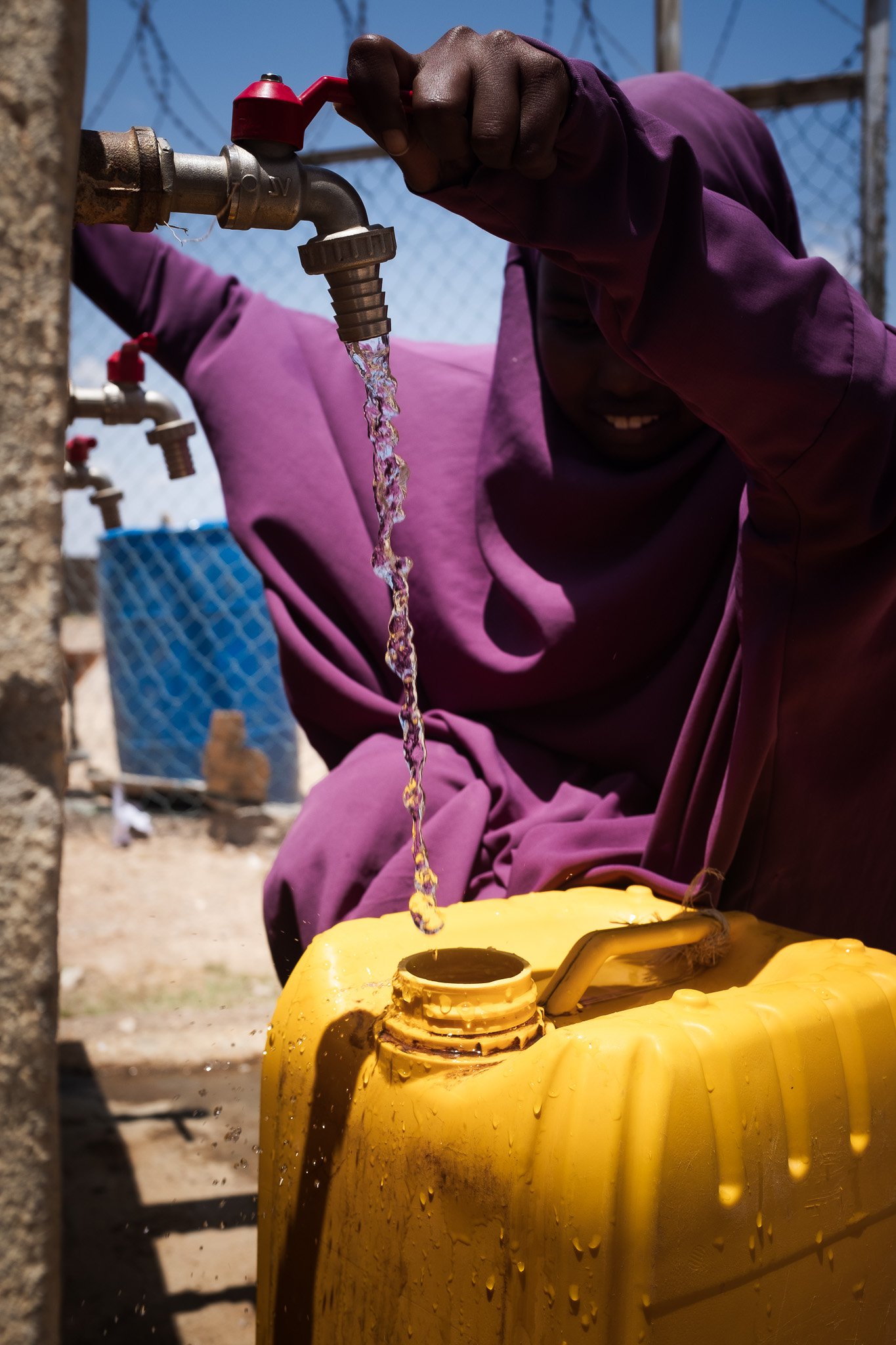DSCF7992-2 A young woman fetches clean water at an Oxfam distribution centre. Photo: Caroline Leal/Oxfam