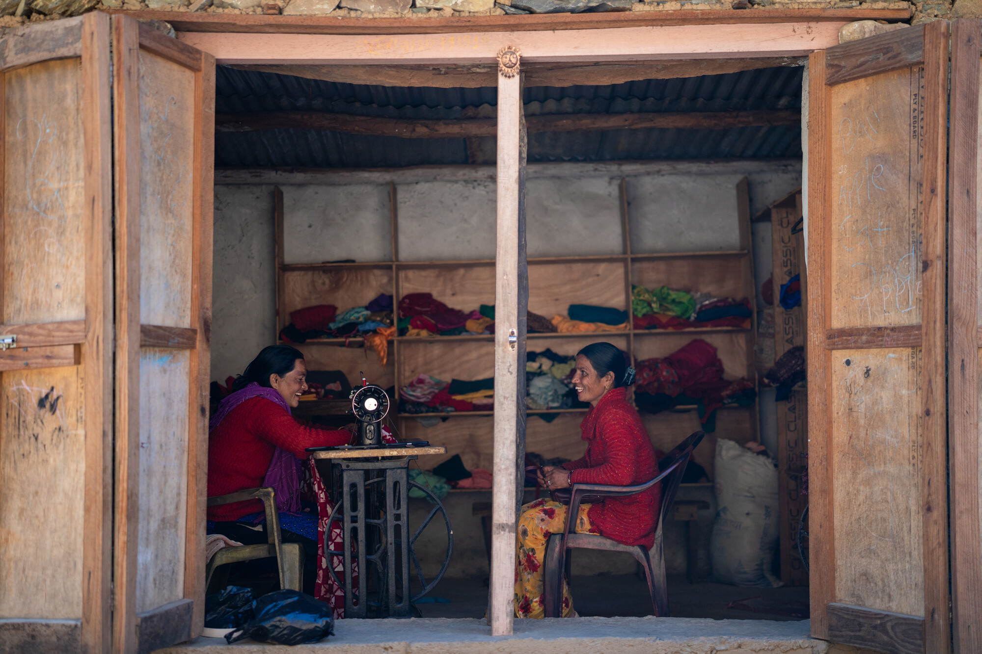 Reshma Kumari Nepali (left) works on her sewing machine in her shop while she meets with Pramila Bhul. Reshma says the funds from the ward council budget that paid for her training and got her a sewing machine helped her start her tailoring business. Photo: Rashik Maharjan/Oxfam