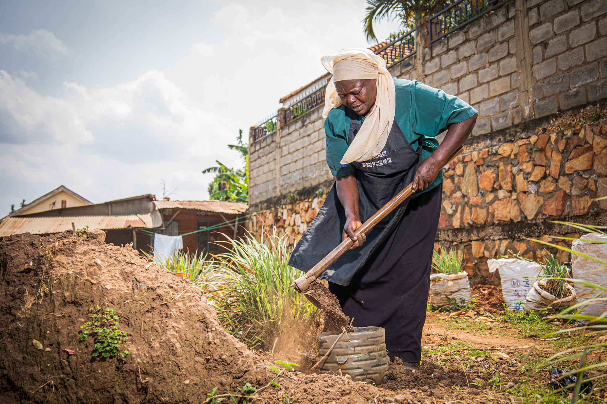 Nakato carefully fills a recycled plastic container with soil to create a planter for her garden.
