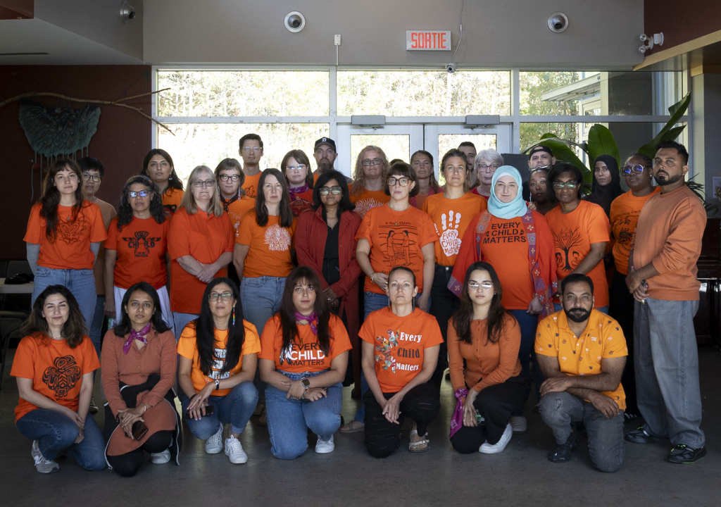 Diverse group of Oxfam Canada staff members posing for a group photo in their orange tshirts.