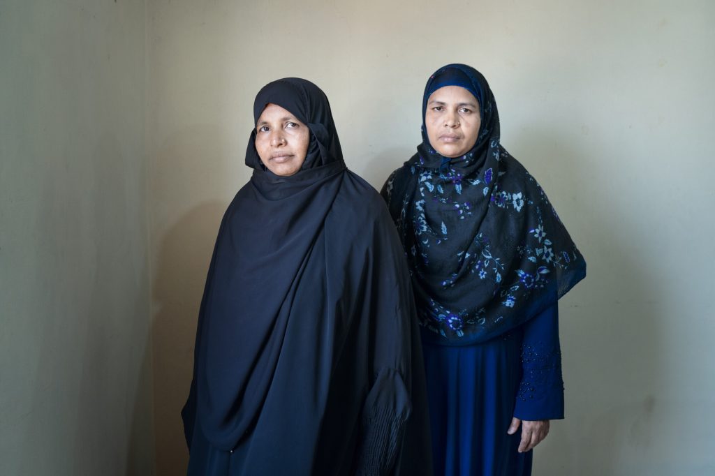 Two women, wearing black clothes, looking at the camera.