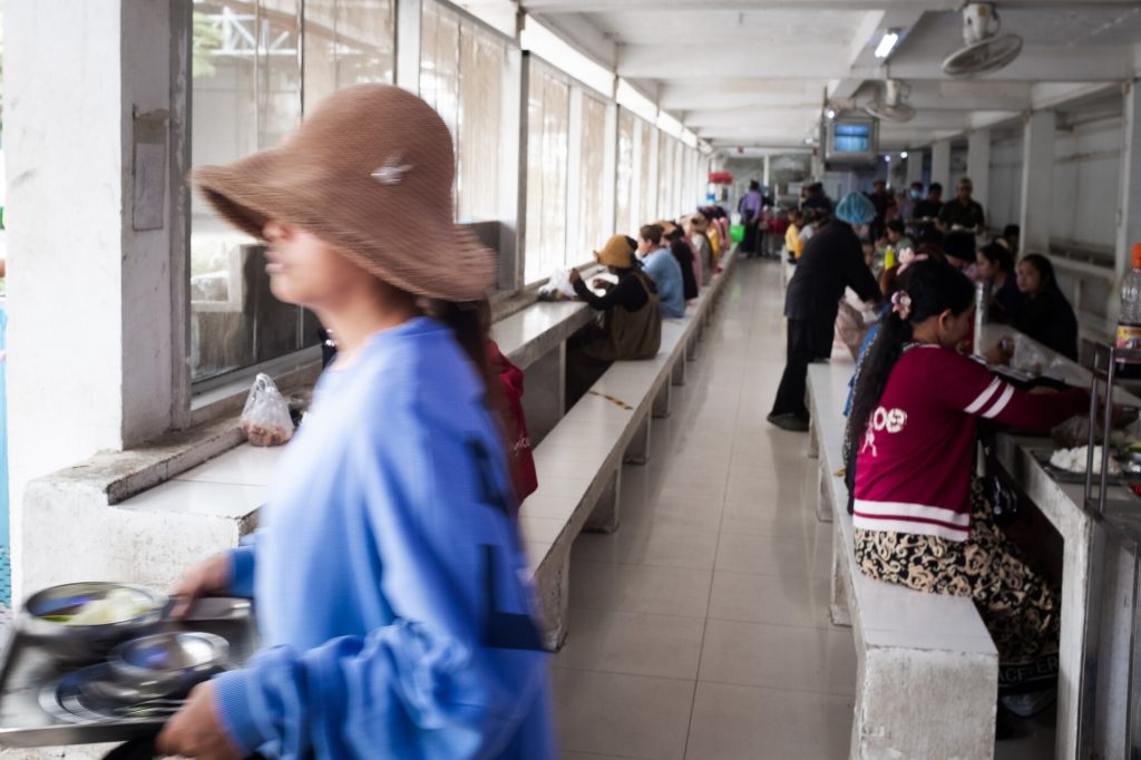 Women eating lunch inside a factory's cafeteria.
