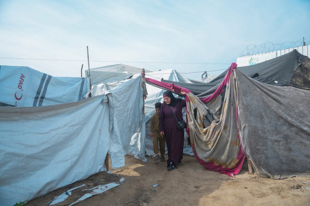 Rawya, a CASH assistance recipient in Gaza gets outside her tent with her children in a makeshift tent camp in Gaza. Photo: Mosab Al-Borno/ Alef Multimedia/ Oxfam