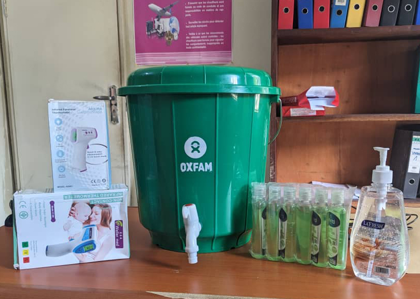 WASH kit supplies in Oxfam office, Goma. The items shown are two infrared thermometers, a handwashing bucket, six 100ml pouch disinfectants (for personal use), and one 500ml office disinfectant. Photo: Tshipson Tshipalaba/ Oxfam
