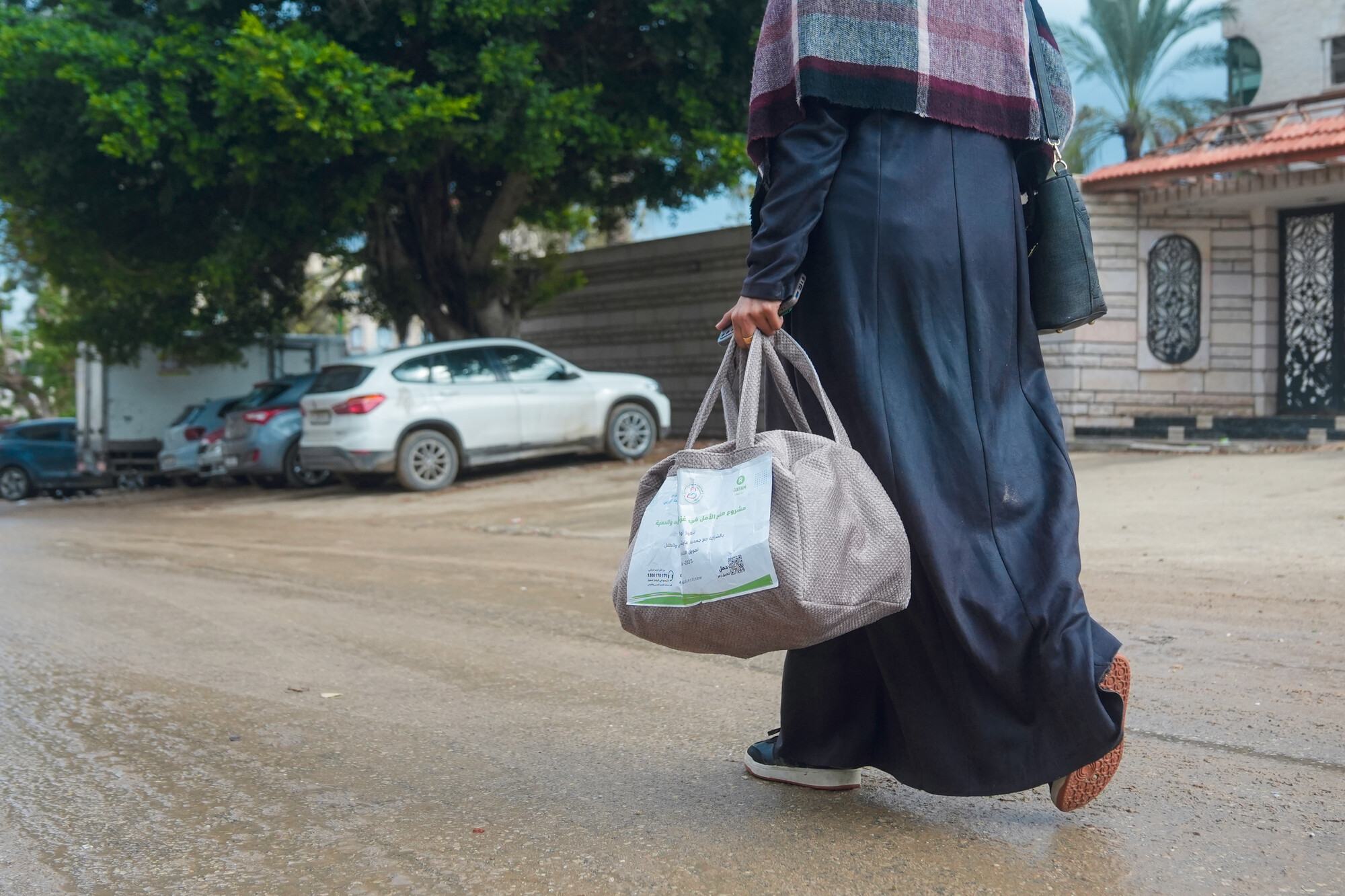 A Palestinian woman in Gaza walks home with a bag of hygiene items provided by Oxfam and the Aisha Association for Women and Child Protection. Mosab Al-Borno / Alef Multimedia / Oxfam