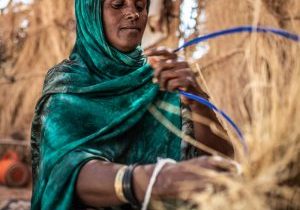 A woman is weaving a basket.
