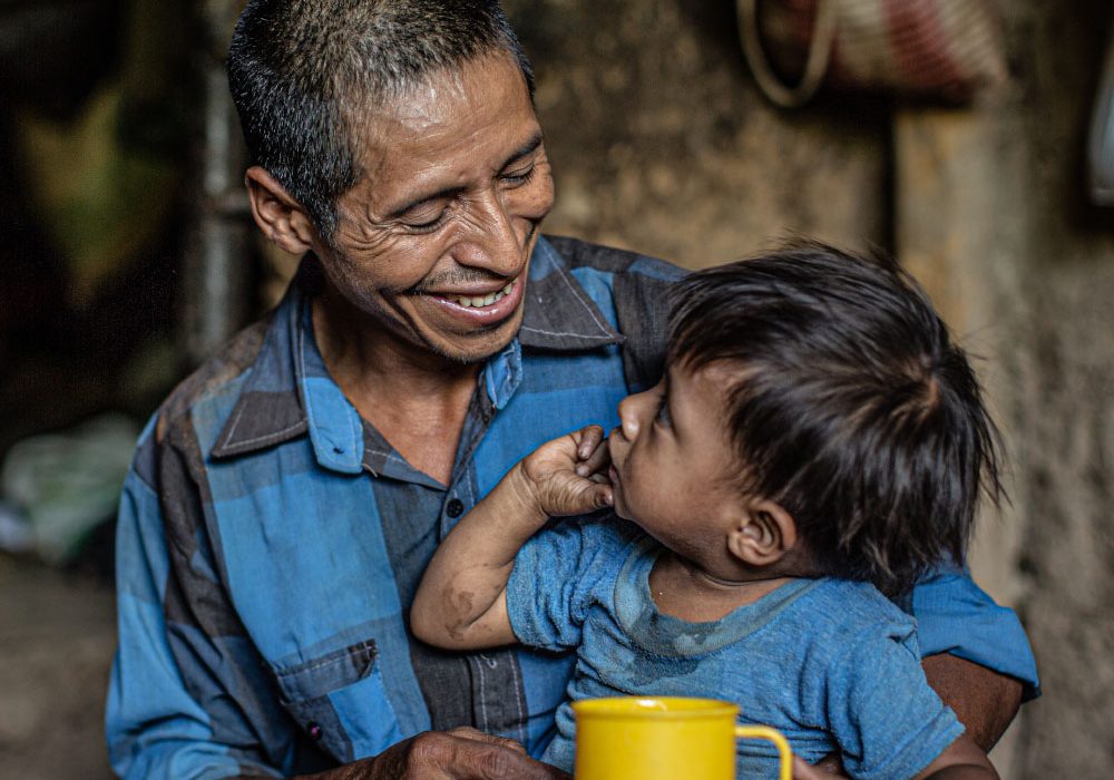 Financials_Hero2 A father smiles at his son who is sitting on his lap.
