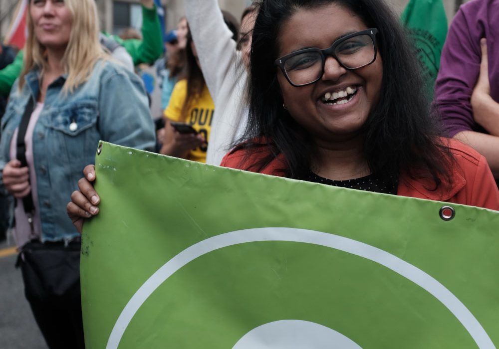 Landing_Card_OxfamYou A woman holding an Oxfam Canada banner smiles for the camera.