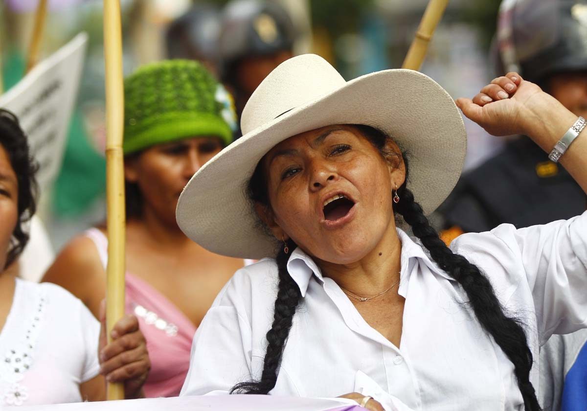 Landing_Slide_Hero A woman wearing heat is seen talking while marching the streets in a protest.