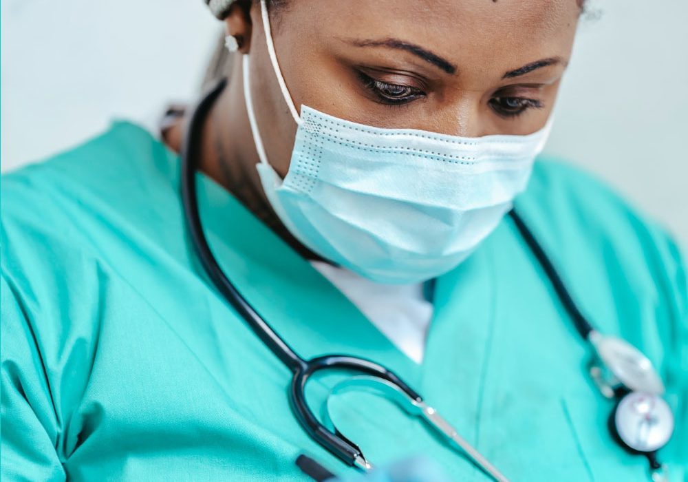Landing_Slide_InvestCare2 A masked nurse writes in her clipboard.