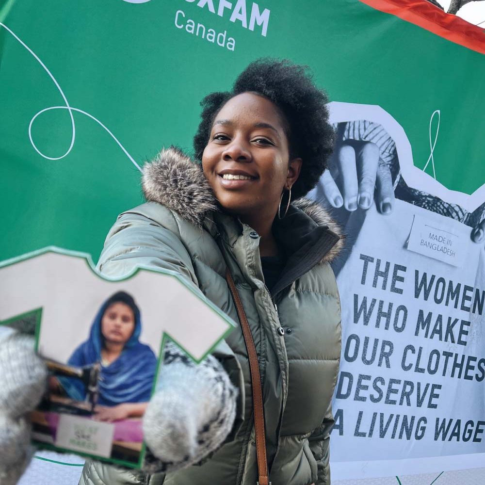 Oxfam and You_WhatSheMakes1 A woman holds an Oxfam branded postcard to the camera.
