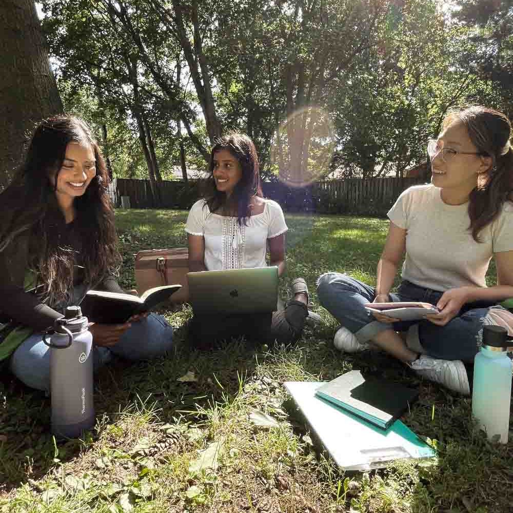 SexualReproductiveRights_HerFuture Three university-aged women are holding a meeting outdoors.