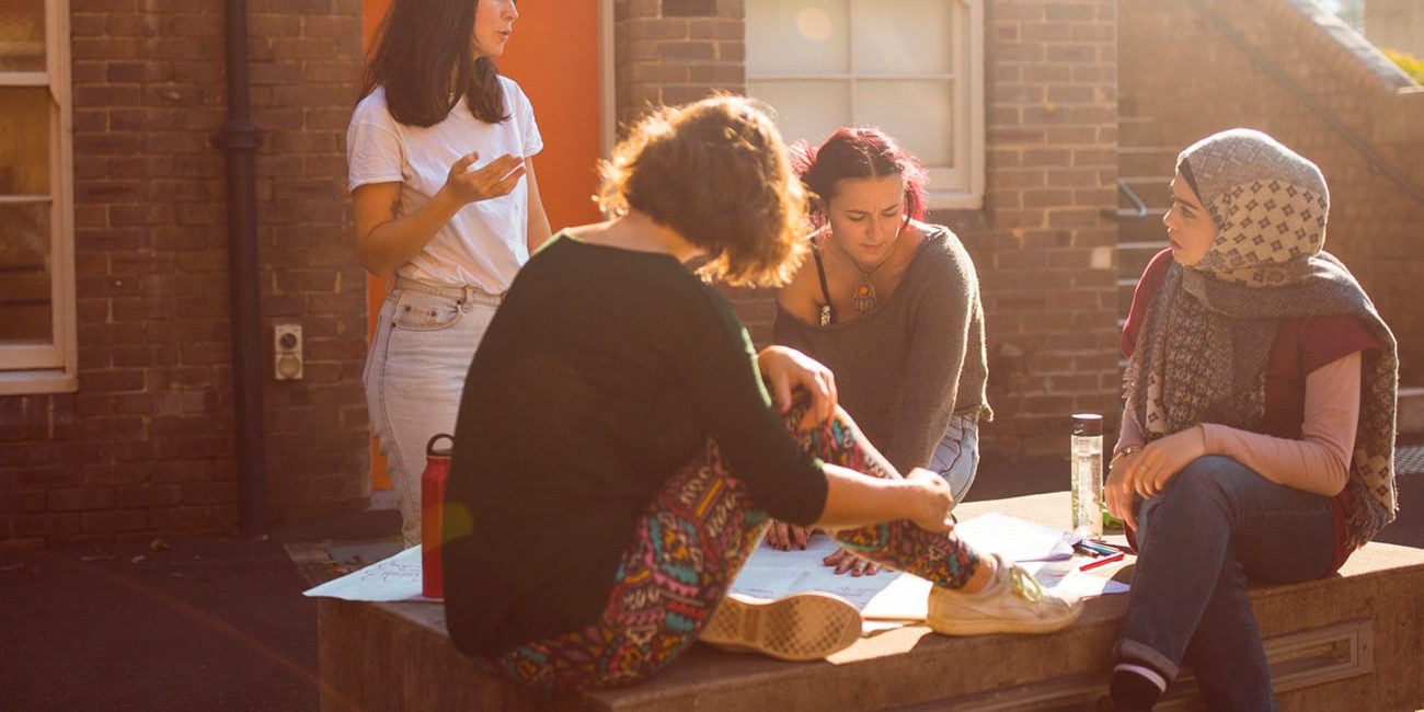 A group of four young women, sitting in a circle and having an planning conversation
